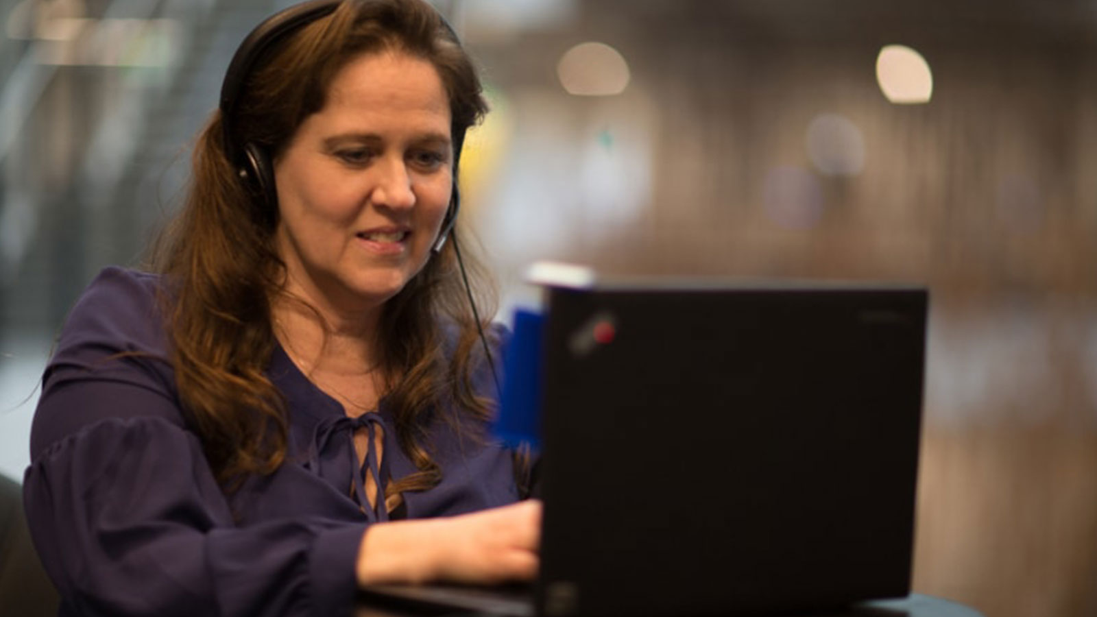 A woman using a assistive hearing device with her laptop